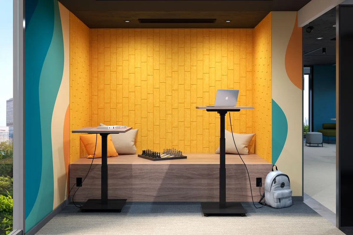 Fotografía de una de las mesas de altura ajustable frente una pared color amarillo con muros de colores.