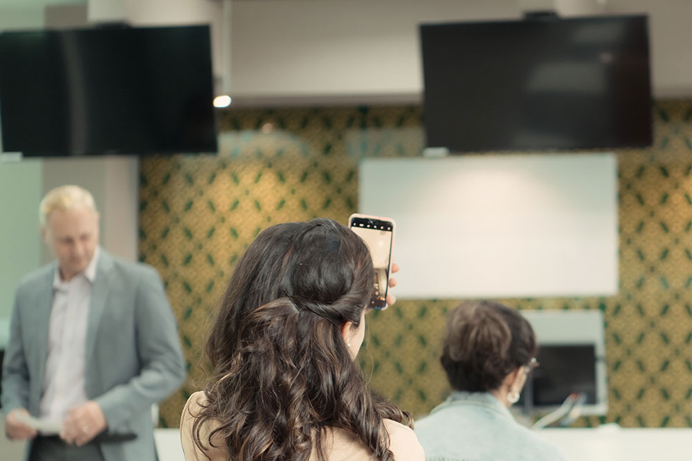 Fotografía desde atrás de una mujer mirando una pantalla mientras está sentada en una de las salas de espera.