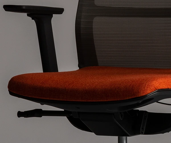 Fotografía de cerca del asiento de una de las sillas de oficina color naranja con respaldo color negro.